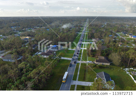 Top view of classical American yellow school bus picking up kids at rural town street stop for their lessons in early morning. Public transport in the USA 113972715