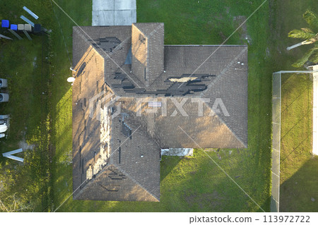 Damaged house roof with missing shingles after hurricane Ian in Florida. Consequences of natural disaster 113972722