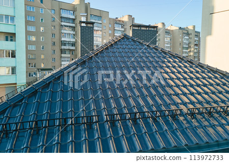 Closeup snow guard for safety in winter on house roof top covered with ceramic shingles. Tiled covering of building 113972733