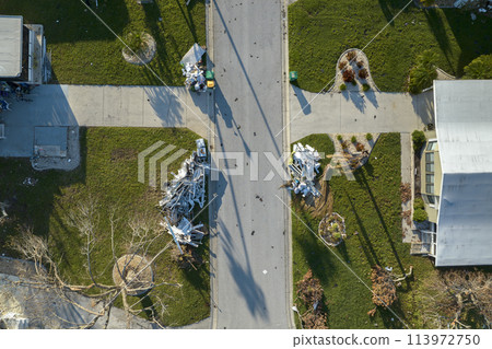 Heaps of debris rubbish on street side near severely damaged by hurricane Ian houses in Florida mobile home residential area. Consequences of natural disaster 113972750