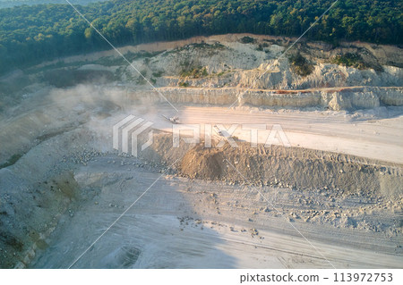 Aerial view of open pit mining site of limestone materials extraction for construction industry with excavators and dump trucks. Aerial view of open pit mining site of limestone materials extraction for construction industry with excavators and dump trucks. 113972753