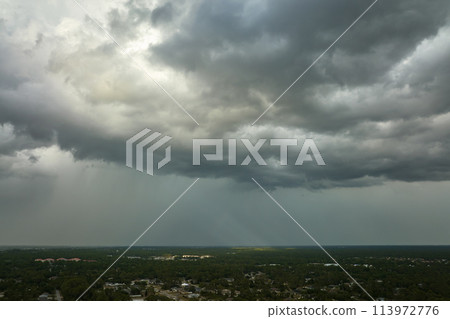 Landscape of dark ominous clouds forming on stormy sky before heavy thunderstorm over rural town area 113972776