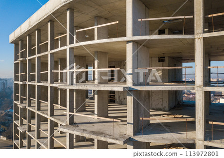 Aerial view of concrete frame of tall apartment building under construction in a city. 113972801