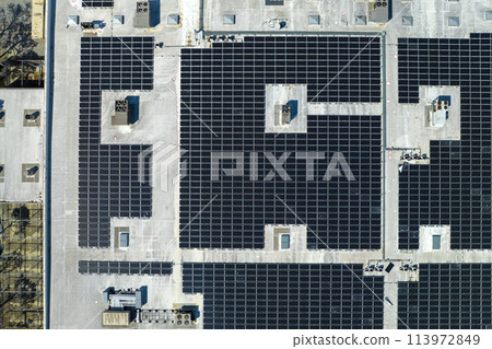 Aerial view of blue photovoltaic solar panels mounted on industrial building roof for producing green ecological electricity. Production of sustainable energy concept 113972849