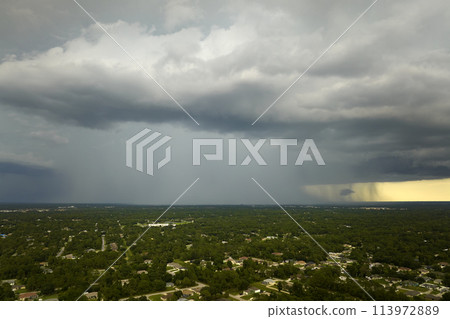 Dark stormy clouds forming on gloomy sky during heavy rainfall season over suburban town area Dark stormy clouds forming on gloomy sky during heavy rainfall season over suburban town area 113972889
