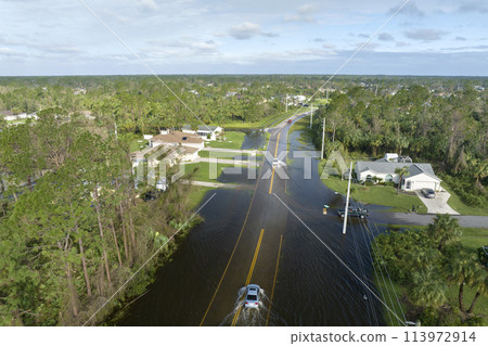 Hurricahe fainfall flooded Florida road with evacuating cars and surrounded with water houses in suburban residential area 113972914
