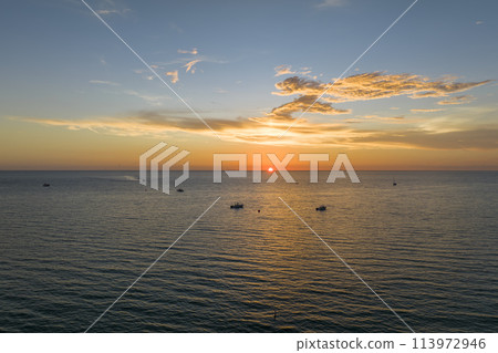 Aerial view of small yachts at sunset floating on sea waves with ripple surface. Motor boats recreation on ocean surface Aerial view of small yachts at sunset floating on sea waves with ripple surface. Motor boats recreation on ocean surface 113972946
