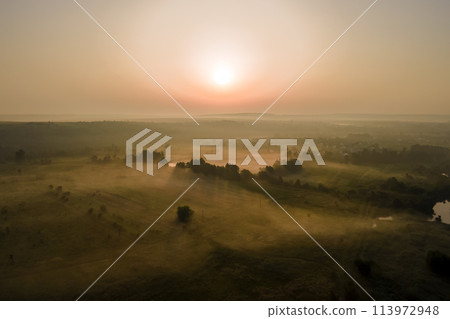 Bright colorful sunset sky with setting sun and vibrant clouds over dark landscape Bright colorful sunset sky with setting sun and vibrant clouds over dark landscape 113972948