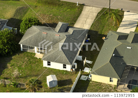 Aerial view of suburban landscape with private homes between green palm trees in Florida quiet residential area Aerial view of suburban landscape with private homes between green palm trees in Florida quiet residential area 113972955