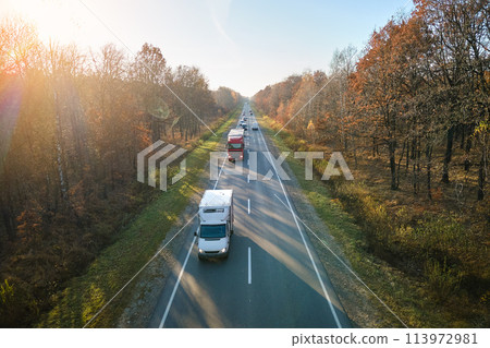 Aerial view of cargo trucks driving on highway hauling goods. Delivery transportation and logistics concept Aerial view of cargo trucks driving on highway hauling goods. Delivery transportation and logistics concept 113972981