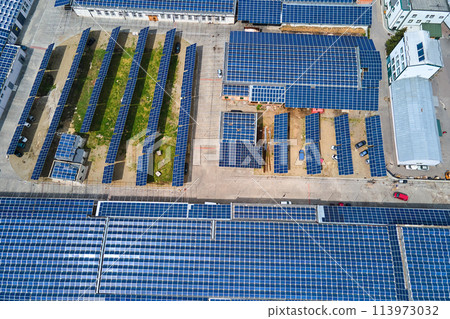 Aerial view of solar power plant with blue photovoltaic panels mounted on industrial building roof for producing green ecological electricity. Production of sustainable energy concept. 113973032