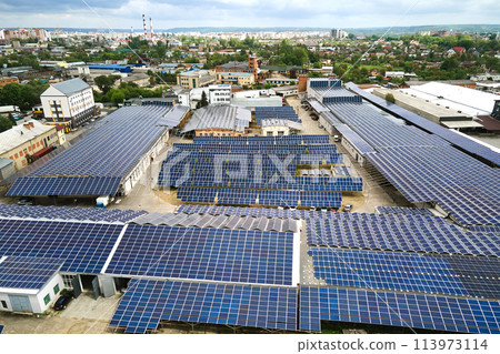 Aerial view of solar power plant with blue photovoltaic panels mounted on industrial building roof for producing green ecological electricity. Production of sustainable energy concept. Aerial view of solar power plant with blue photovoltaic panels mounted on industrial building roof for producing green ecological electricity. Production of sustainable energy concept. 113973114