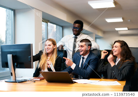 Diverse office team excitedly reacts to successful deal at computer, happy multiracial colleagues celebrating growth, businessman, businesswoman fist pump in corporate meeting, share victory moment. 113973540