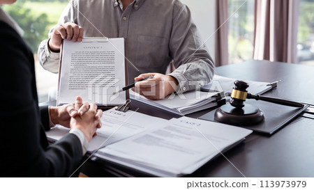 Male lawyer showing contract and pointing the signature box for signing while explaining and consultation about legislation agreement and terms data of business contract to businessman in law firm 113973979