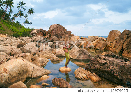 Trans sexual black fashion model poses in natural pool surrounded by rocks on tropical island. Androgynous ethnic fashion model stands on stone in the middle of backwater at exotic scenic location. Trans sexual black fashion model poses in natural pool surrounded by rocks on tropical island. Androgynous ethnic fashion model stands on stone in the middle of backwater at exotic scenic location. 113974025
