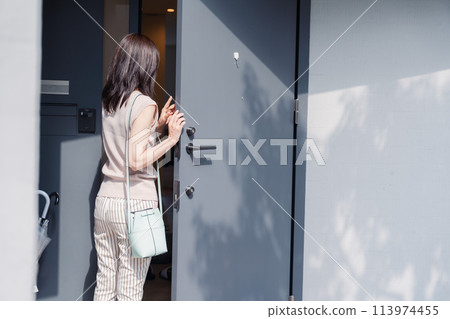 Young woman opening the front door of her house Young woman opening the front door of her house 113974455