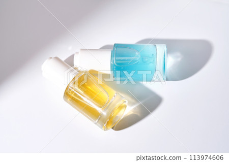 Yellow and blue serums with pipettes against the background of the sun. 113974606