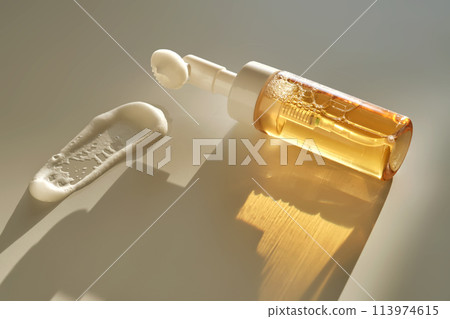 Beige facial foam with a dispenser and brush in the rays of the setting sun. 113974615