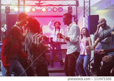 Young friends group partying on dancefloor and improvising dance battle in nightclub. Diverse people clubbing at discotheque while relaxing and enjoying nightlife leisure Young friends group partying on dancefloor and improvising dance battle in nightclub. Diverse people clubbing at discotheque while relaxing and enjoying nightlife leisure 113975300