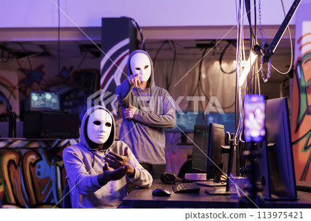 Internet thieves streaming ransom and demanding for payment and privacy information. Criminals in anonymous masks threatening to share personal password on mobile phone camera 113975421