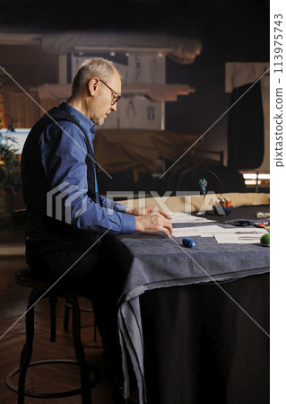 Fashion designer working on upcoming sartorial project for runway show, conceptualizing different garment combinations in atelier workspace. Creative couturier working in professional tailoring studio Fashion designer working on upcoming sartorial project for runway show, conceptualizing different garment combinations in atelier workspace. Creative couturier working in professional tailoring studio 113975743