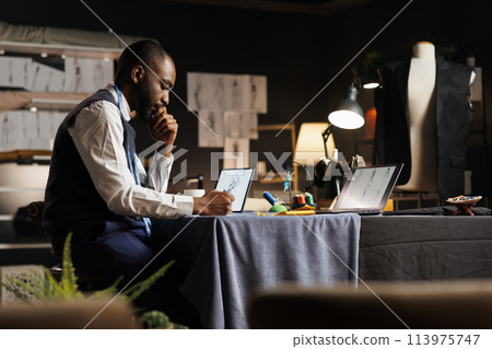 Dressmaker handdrawing sketch of upcoming custom made sartorial collection in atelier shop workspace. Experienced fashion designer creating handmade creative fashion collection Dressmaker handdrawing sketch of upcoming custom made sartorial collection in atelier shop workspace. Experienced fashion designer creating handmade creative fashion collection 113975747