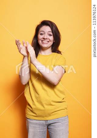 Cheerful female individual clapping hands to celebrate achievement while looking at camera. Caucasian woman with positive emotions applauding and doing appreciation claps for her friend. Cheerful female individual clapping hands to celebrate achievement while looking at camera. Caucasian woman with positive emotions applauding and doing appreciation claps for her friend. 113976124
