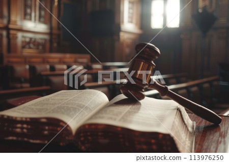 Wooden gavel sits on top of an open law book in a courtroom, symbolizing legal authority and justice 113976250