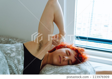 morning, young woman waking up in bed with natural hair under arms 113976909