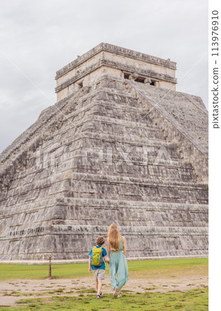 Beautiful tourist woman and her son observing the old pyramid and temple of the castle of the Mayan architecture known as Chichen Itza these are the ruins of this ancient pre-columbian civilization 113976910