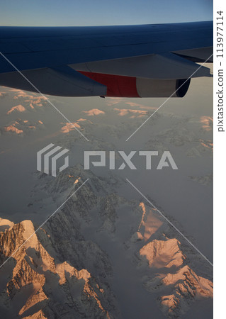COPENHAGEN, DENMARK - 24 NOV 2018: Aeroplane window view with plane wing flying over the icebergs of Greenland at sunset with aerial perspective COPENHAGEN, DENMARK - 24 NOV 2018: Aeroplane window view with plane wing flying over the icebergs of Greenland at sunset with aerial perspective 113977114