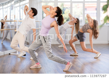 Group of men and women dance an energetic hip-hop dance in studio. Modern dance lesson Group of men and women dance an energetic hip-hop dance in studio. Modern dance lesson 113977287