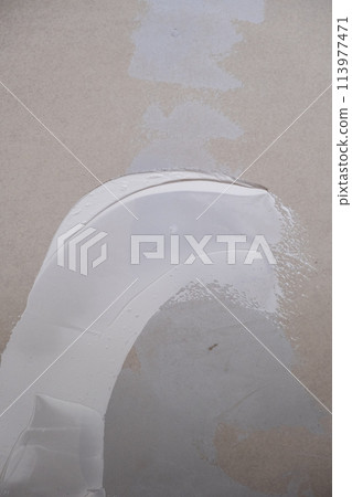 Applying decorative putty. White abstract texture of surface covered with putty Applying decorative putty. White abstract texture of surface covered with putty 113977471