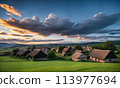 Panoramic top view of an old small abandoned ruined village on the hills with thatched roof huts at sunset with clouds in the sky 113977694