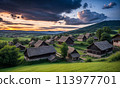 Panoramic top view of an old small abandoned ruined village on the hills with thatched roof huts at sunset with clouds in the sky 113977701