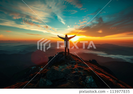Man's silhouette with raised arms celebrating on a mountain top at sunrise 113977835