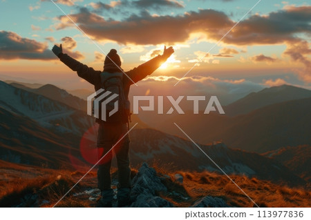Man with arms raised in celebration on the summit during a picturesque sunset 113977836