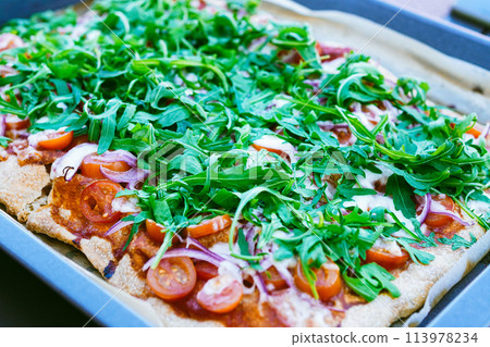 Enjoy a pizza party with homemade pizza with arugula, fresh tomatoes, and red onions 113978234