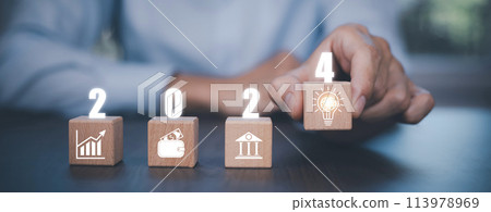 Concept 2024, Businessman touch square wood and icon on office background, Money spending planning, plant growing up on coins and investment budget, Save money for prepare in the future, new year 113978969