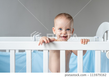 Laughing baby reaching out from his crib Laughing baby reaching out from his crib 113979162