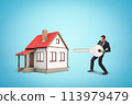 Businessman standing near one-storey cottage and ready to open it with huge key on blue background. 113979479