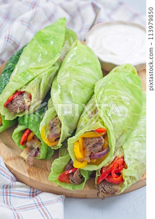 Healthy cabbage leaves wraps with beef, vegetables and cheese, served with plain yogurt, vertical 113979850