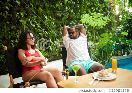 Restful couple sunbathing at resort Restful couple sunbathing at resort 113981356