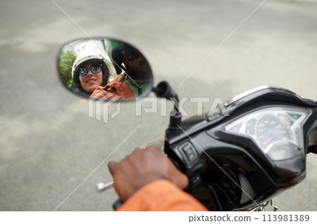 Reflection of couple in motorbike mirror 113981389