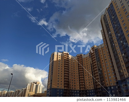High rise buildings on a background of blue sky with white clouds. High rise buildings on a background of blue sky with white clouds. 113981466