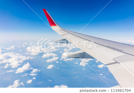 View from the airplane window at a beautiful cloudy sky and the airplane wing 113981704