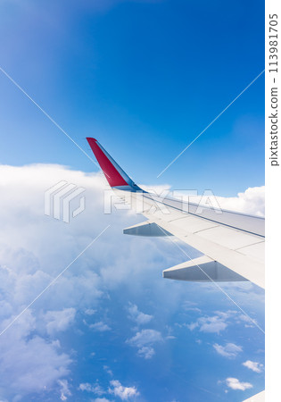 View from the airplane window at a beautiful cloudy sky and the airplane wing 113981705