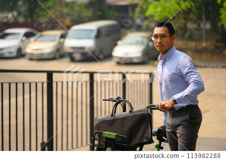 Businessman pushing bicycle while going to work on a sunny morning. Eco transportation Businessman pushing bicycle while going to work on a sunny morning. Eco transportation 113982288