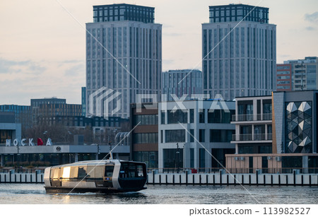 Electric river tram on the Moskva River at sunset on an autumn evening. Electric river tram on the Moskva River at sunset on an autumn evening. 113982527