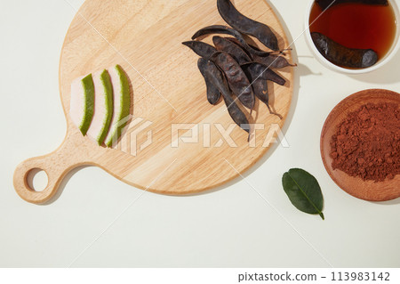 High angle shot at wooden chopping board with blank space for displaying product made from locust. Locust extract is often used in formulas for shampoos and hair conditioners High angle shot at wooden chopping board with blank space for displaying product made from locust. Locust extract is often used in formulas for shampoos and hair conditioners 113983142